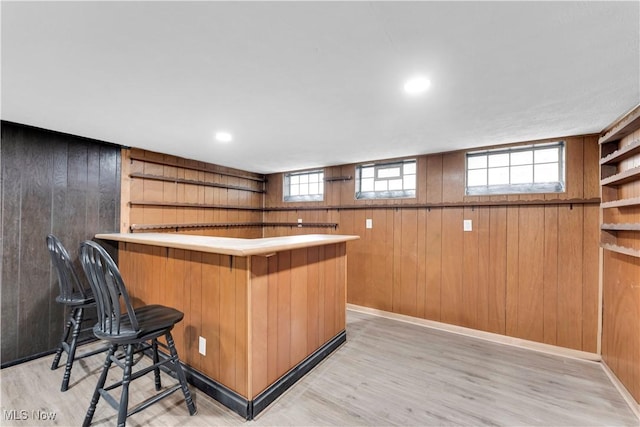indoor dry bar with wooden walls, light wood-style floors, and plenty of natural light