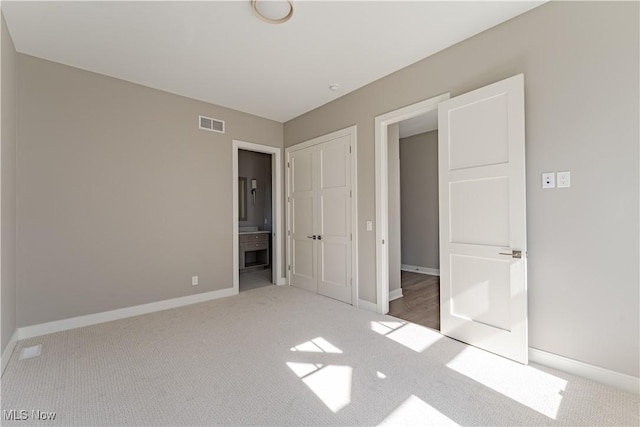 unfurnished bedroom with carpet flooring, baseboards, and ensuite bath