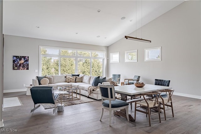 dining room with baseboards, wood finished floors, and high vaulted ceiling