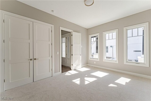 unfurnished bedroom with carpet, baseboards, and a closet