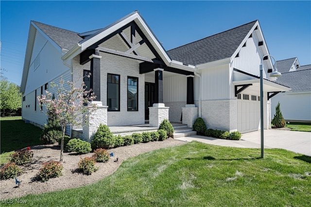 view of front of house with concrete driveway, a front yard, roof with shingles, and a garage