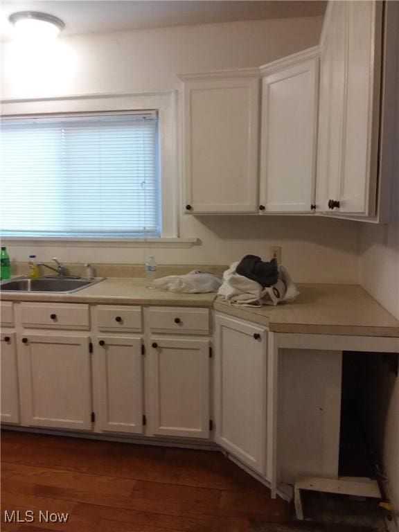 kitchen featuring a sink, white cabinets, light countertops, and dark wood-type flooring