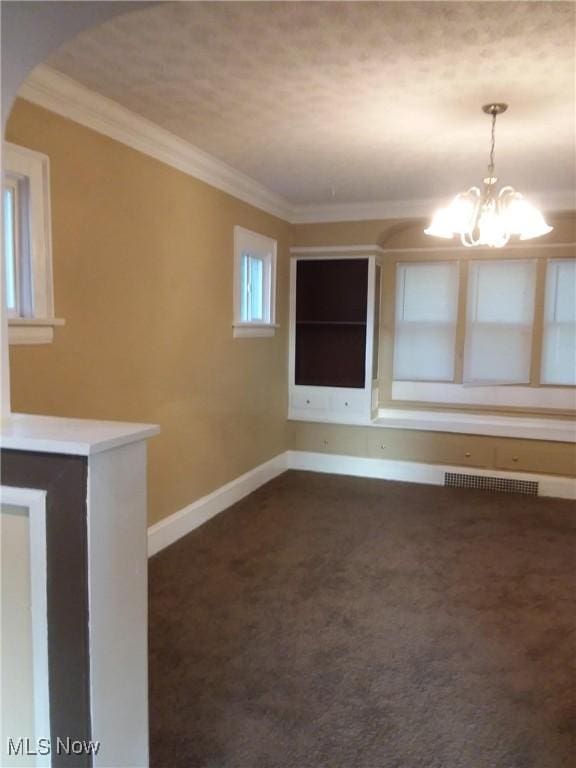 unfurnished room with a chandelier, crown molding, baseboards, dark carpet, and arched walkways