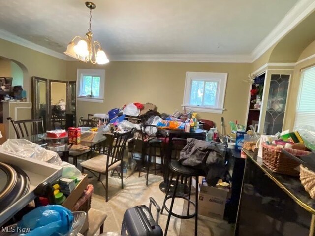 dining space with plenty of natural light, a chandelier, arched walkways, and crown molding