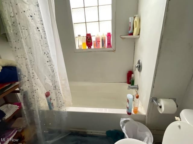 bathroom with toilet and shower / bath combination with curtain