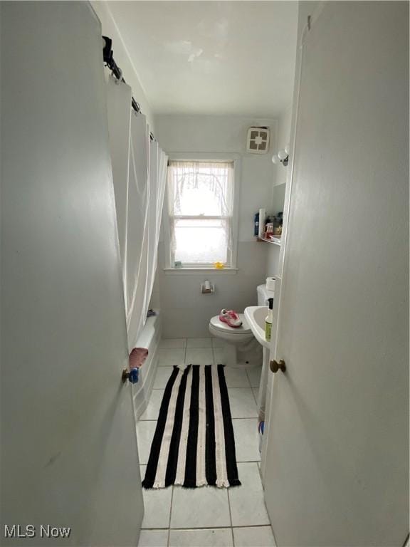 bathroom with tile patterned flooring, toilet, and shower / tub combo with curtain