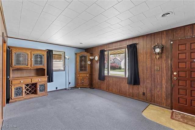 unfurnished living room with carpet floors, baseboards, and wooden walls