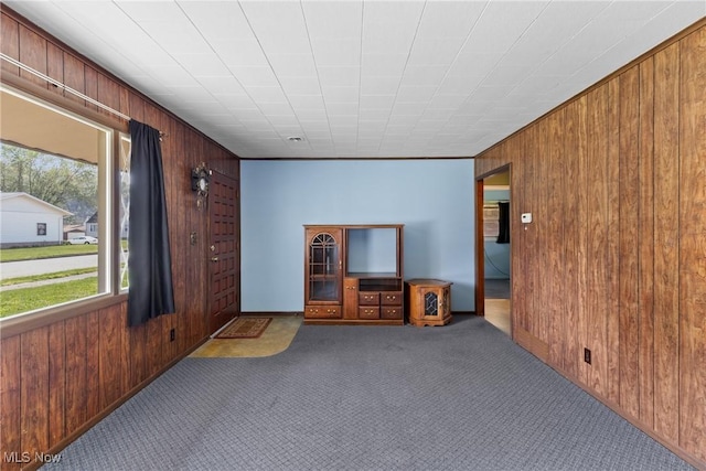 carpeted spare room with wooden walls