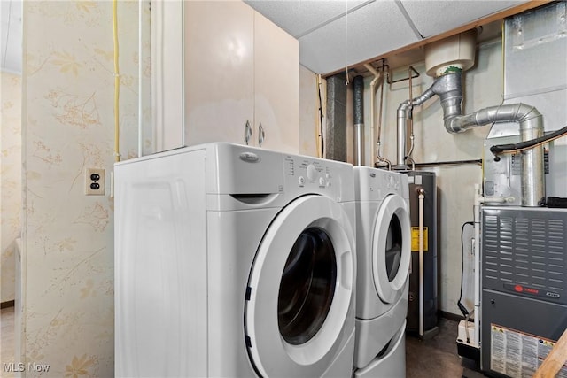 washroom with washer and clothes dryer, water heater, and cabinet space