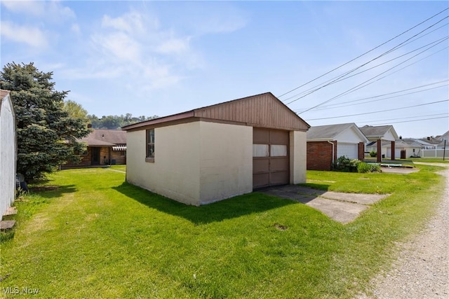 view of home's exterior featuring a detached garage, a yard, and an outbuilding