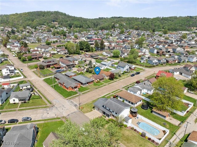 view of property location with nearby suburban area and a forest