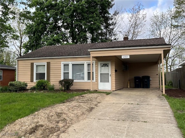 bungalow-style house featuring driveway, fence, a carport, and a chimney