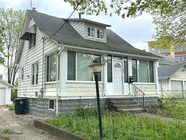 view of front of home featuring entry steps, an outdoor structure, and roof with shingles