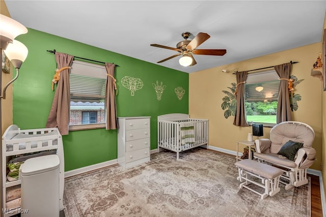 3475 Clague Rd, North Olmsted, OH 44070 - bedroom with a crib, baseboards, a ceiling fan, and wood finished floors