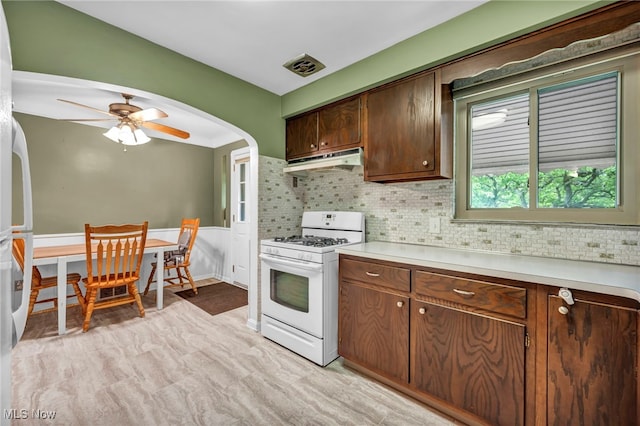 3475 Clague Rd, North Olmsted, OH 44070 - kitchen with white range with gas stovetop, under cabinet range hood, light countertops, arched walkways, and wainscoting
