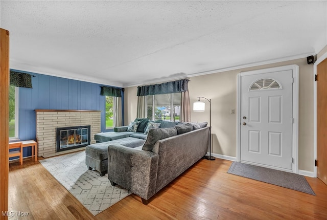 3475 Clague Rd, North Olmsted, OH 44070 - living area with wood finished floors, a textured ceiling, baseboards, ornamental molding, and a brick fireplace