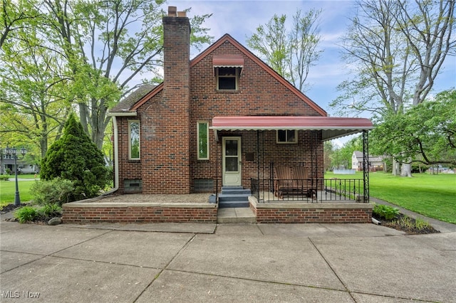 3475 Clague Rd, North Olmsted, OH 44070 - tudor-style house featuring a front lawn, a chimney, brick siding, and a porch