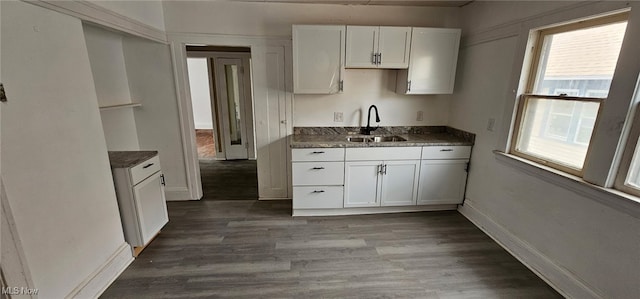 kitchen featuring a sink, white cabinets, wood finished floors, and baseboards