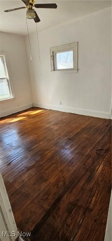 spare room with healthy amount of natural light, a ceiling fan, wood finished floors, and baseboards
