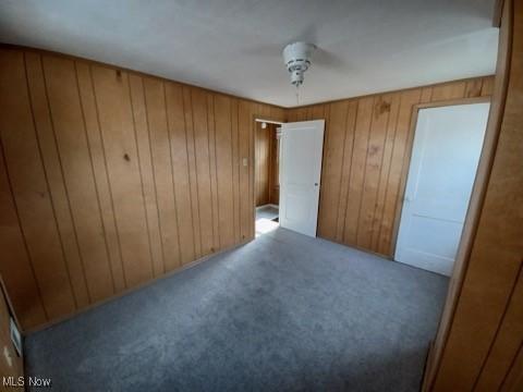 438 Elberen St, Youngstown, OH 44509 - unfurnished bedroom with carpet floors, wood walls, and ceiling fan