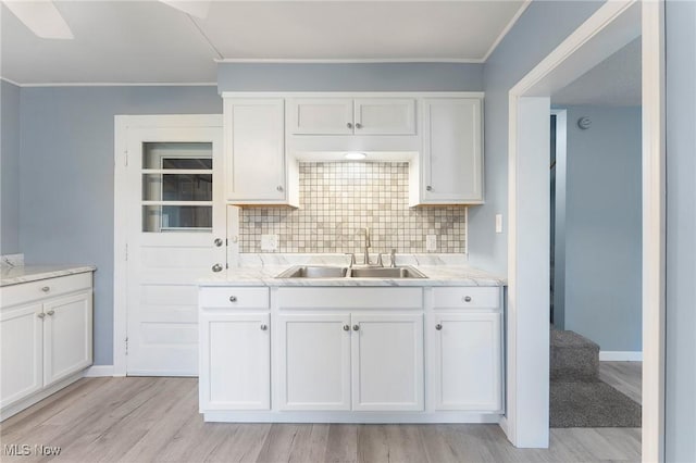 215 Holford Ave, Niles, OH 44446 - kitchen featuring a sink, decorative backsplash, white cabinets, light wood-style floors, and ornamental molding