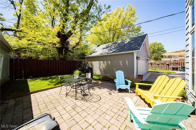 view of patio featuring an outdoor structure, outdoor dining area, and a garage