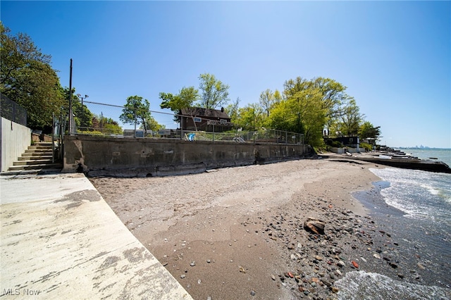view of community featuring stairway, fence, and a water view