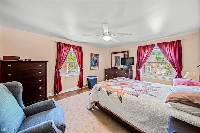 bedroom featuring multiple windows, wood finished floors, baseboards, and ceiling fan