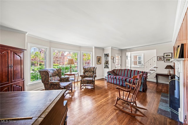 living room with plenty of natural light, dark wood finished floors, stairs, a fireplace with flush hearth, and ornamental molding