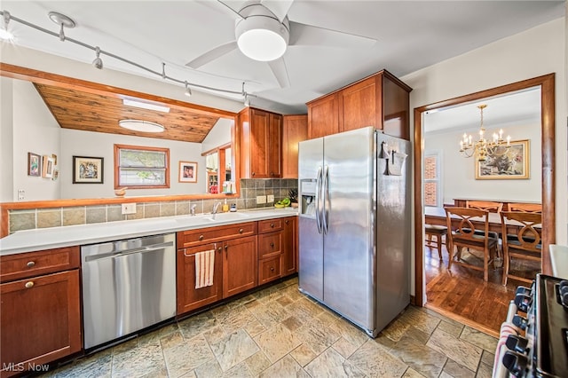 kitchen featuring appliances with stainless steel finishes, a sink, vaulted ceiling, light countertops, and brown cabinetry