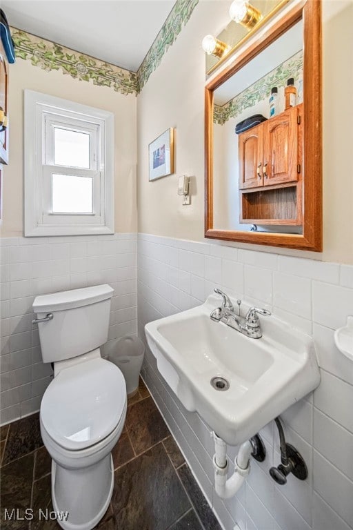 bathroom with tile walls, wainscoting, and toilet