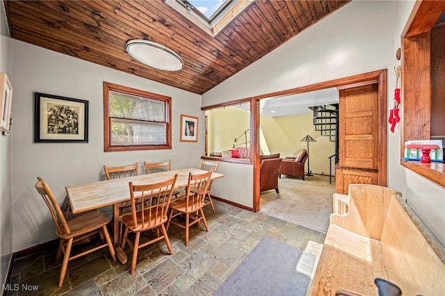 dining area featuring stone tile flooring, lofted ceiling, baseboards, and wooden ceiling