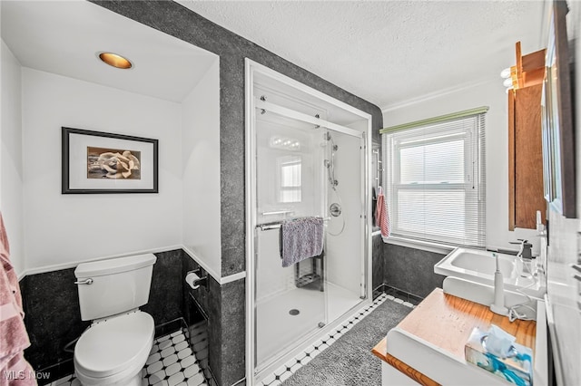 full bathroom featuring a stall shower, toilet, a textured ceiling, a wainscoted wall, and vanity