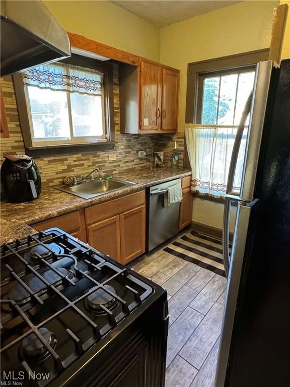 kitchen with freestanding refrigerator, dishwasher, gas stove, a sink, and under cabinet range hood