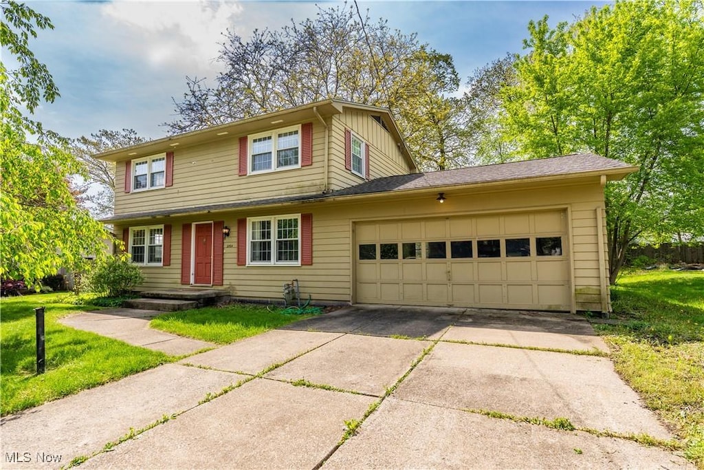 traditional home with driveway, an attached garage, and a front lawn