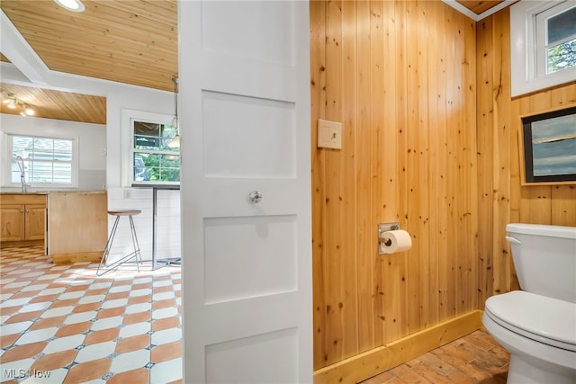 bathroom featuring wooden ceiling, wood walls, toilet, and a sink