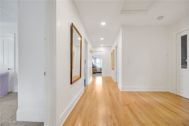 hallway featuring light wood-style flooring, baseboards, and recessed lighting