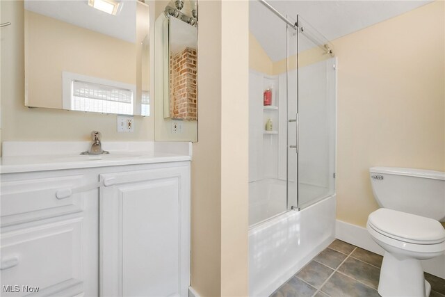 bathroom featuring toilet, enclosed tub / shower combo, vanity, tile patterned flooring, and baseboards