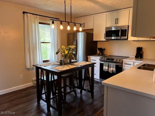 206 Anderson Ave, Bethesda, OH 43719 - kitchen featuring stainless steel appliances, a textured ceiling, light countertops, white cabinetry, and hanging light fixtures