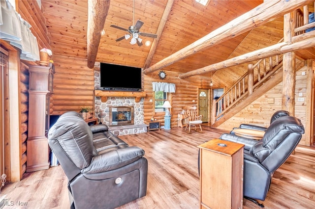 living area featuring rustic walls, stairway, wood ceiling, a stone fireplace, and wood finished floors