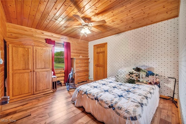 bedroom with wood ceiling, light wood finished floors, wallpapered walls, ceiling fan, and log walls