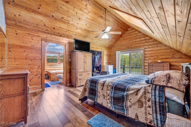 bedroom featuring wood ceiling, lofted ceiling, connected bathroom, rustic walls, and a walk in closet