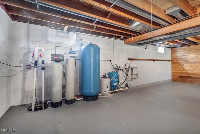 unfinished below grade area featuring a water pressure tank, concrete block wall, and drainage system