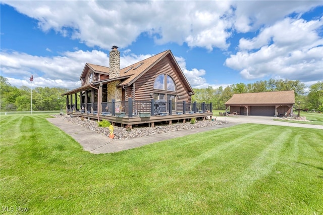 back of property with log siding, a chimney, a lawn, a detached garage, and a wooden deck
