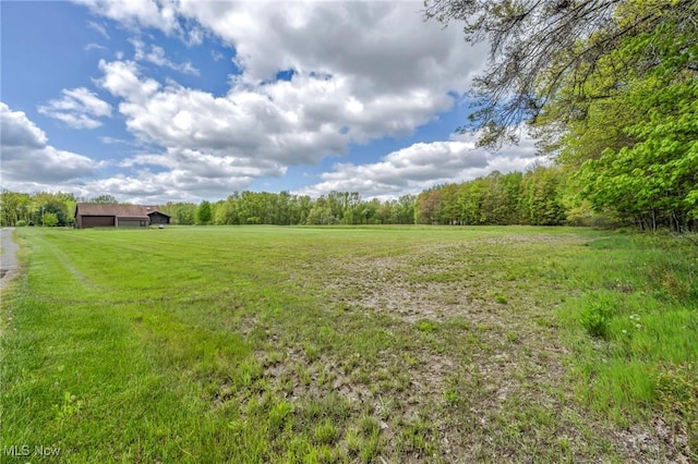 view of grassy yard with a view of countryside and a wooded view