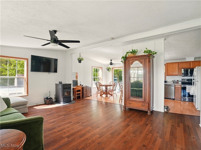 living area featuring a ceiling fan, a textured ceiling, dark wood-style floors, and a wood stove