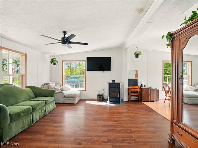 living room featuring a wood stove, a ceiling fan, wood finished floors, and a textured ceiling