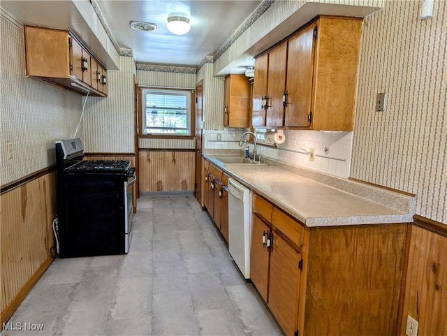 316 S Inglewood Ave, Austintown, OH 44515 - kitchen with stainless steel gas range oven, a sink, white dishwasher, wallpapered walls, and brown cabinetry