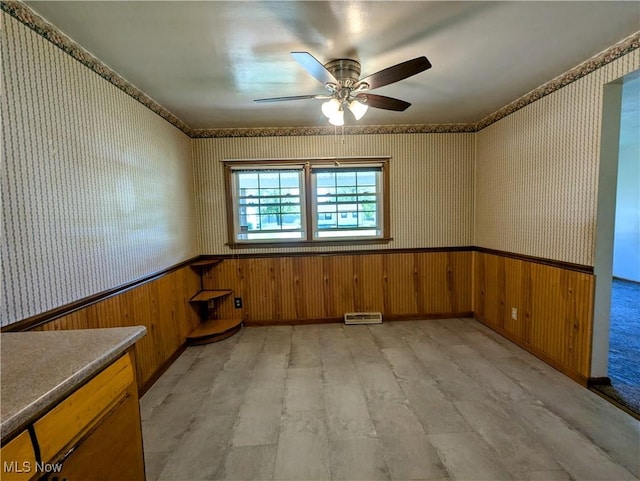 316 S Inglewood Ave, Austintown, OH 44515 - spare room with wallpapered walls, a wainscoted wall, light wood-type flooring, a ceiling fan, and wood walls