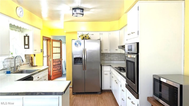 6291 Veterans Blvd, Chester, WV 26034 - kitchen featuring appliances with stainless steel finishes, a sink, backsplash, light wood-style floors, and white cabinetry